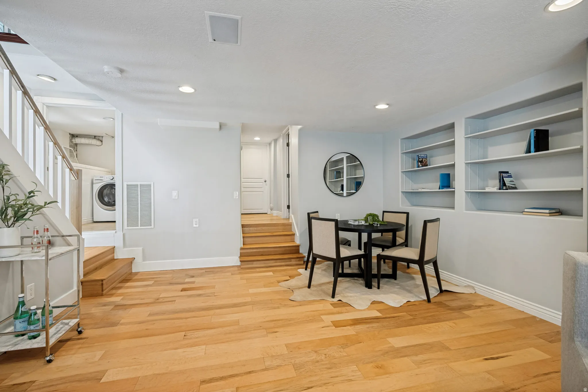 Hardwood flooring throughout, built-in shelving, recessed lighting, and a visible laundry area