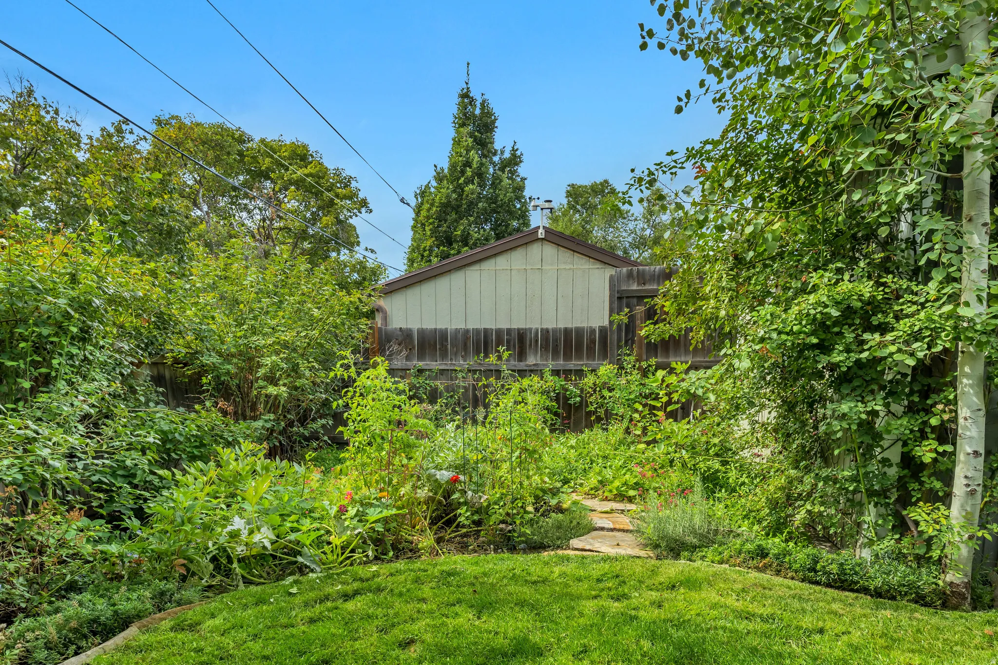Expansive yard featuring a manicured lawn, established garden beds, and a flagstone pathway