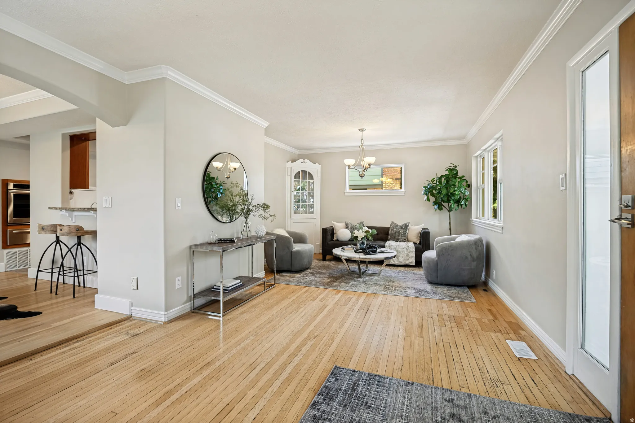 Light wood-finish flooring, crown molding, and recessed lighting enhance the living area