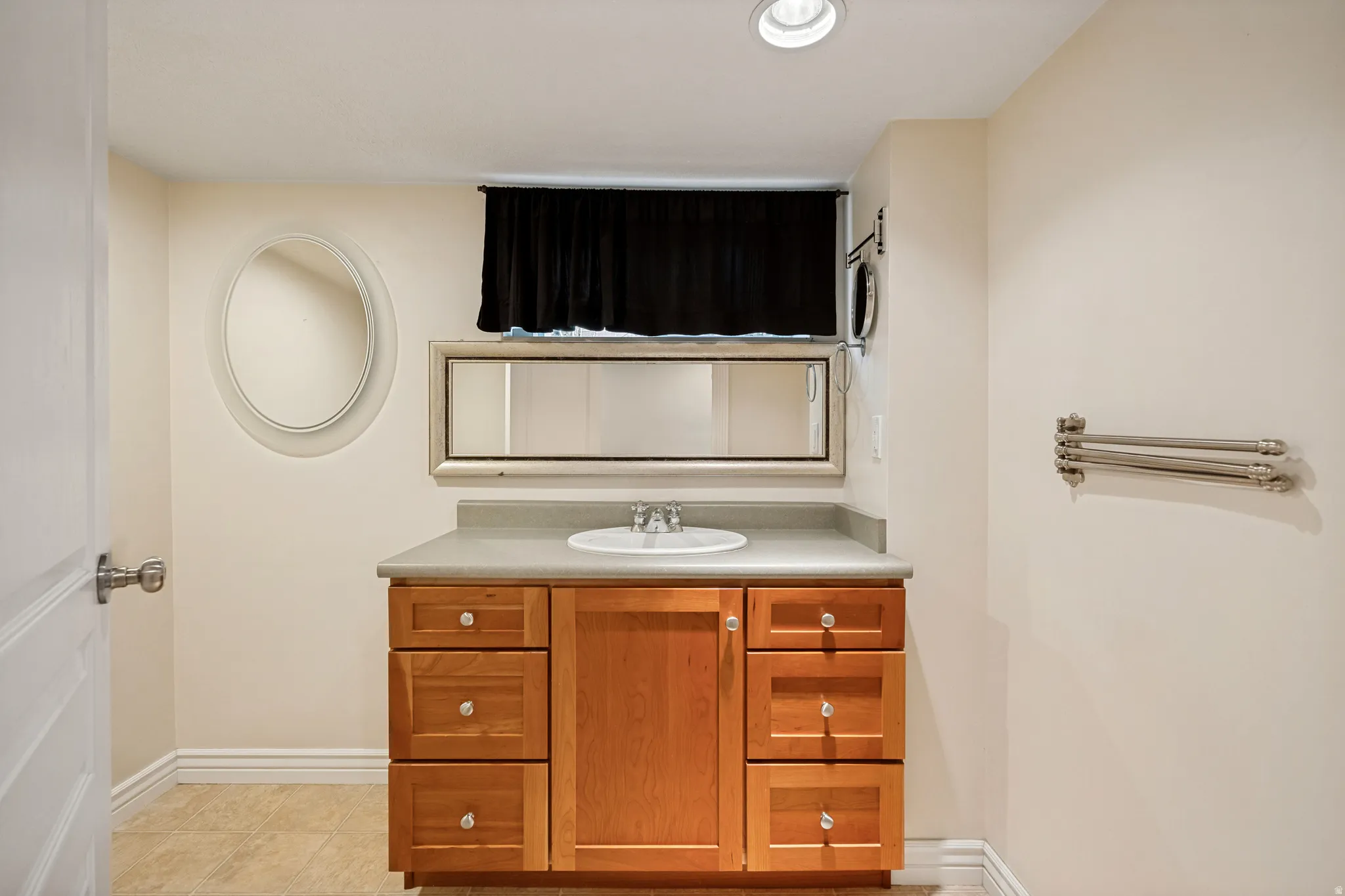 Basement half bath with wood-finish vanity, a rectangular undermount sink and a solid surface countertop