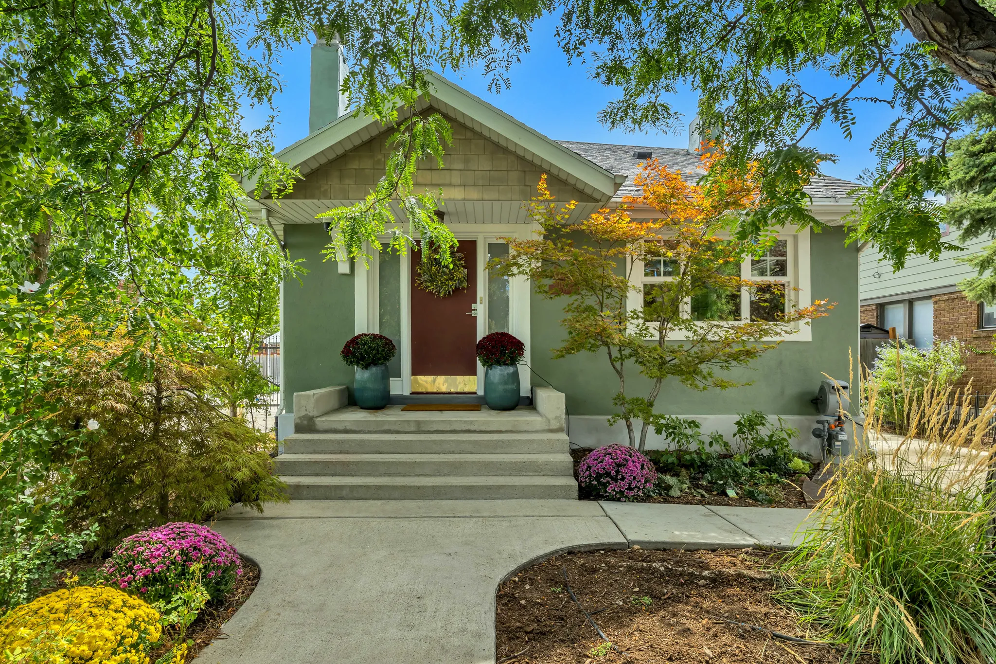 Stucco exterior with a wood-shingle gable, concrete entry steps, and a winding concrete pathway