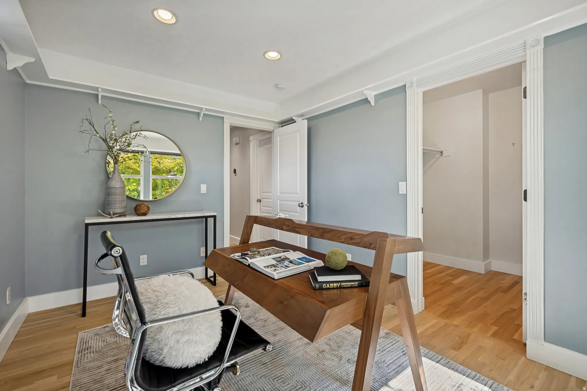 Recessed ceiling lighting, wood-finish flooring, built-in closet shelving, and a console table with a marble-finish top