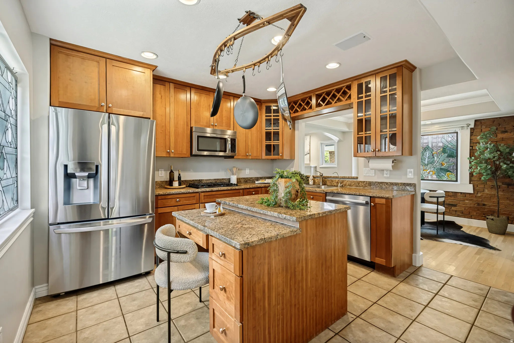 Kitchen featuring tile flooring, stainless steel appliances, wood cabinetry, stone countertops, and a built-in wine rack