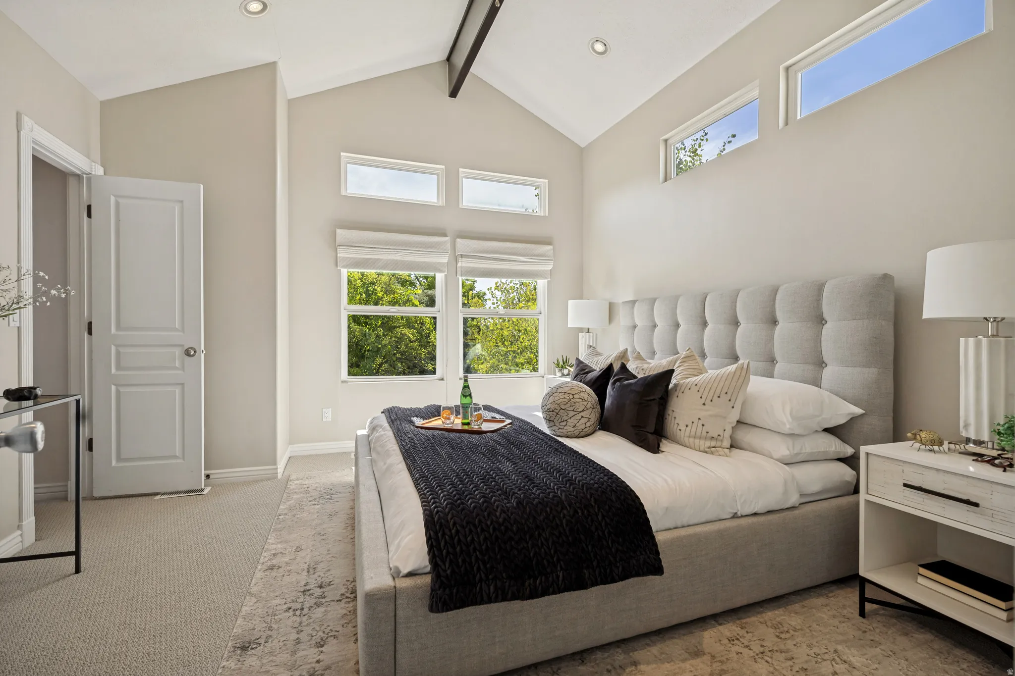 Primary bedroom with vaulted ceiling and recessed lighting