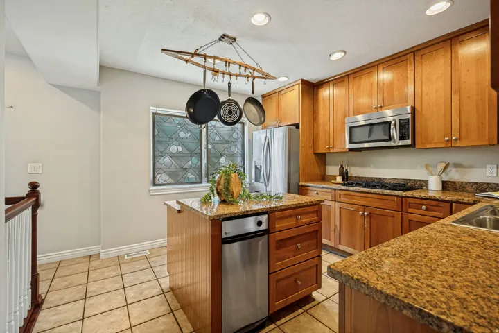 Kitchen featuring wood cabinetry, stainless steel appliances, a center island with a built-in dishwasher, and granite countertops