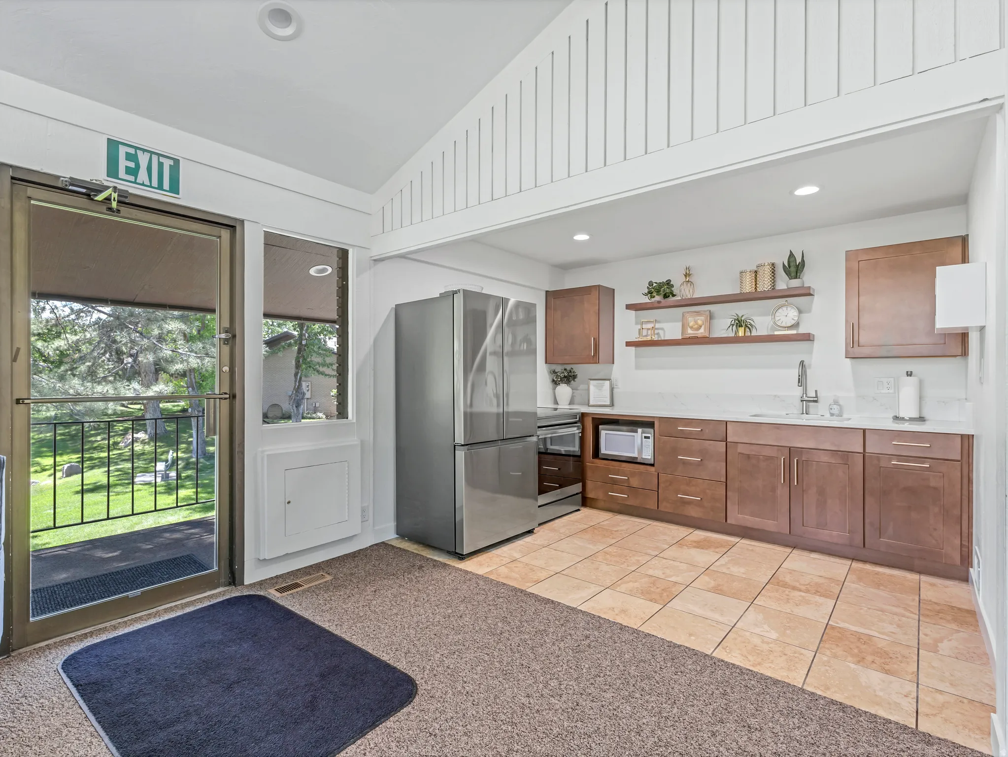Kitchenette featuring stainless steel appliances, wood-finish cabinetry, white countertops, and tile flooring