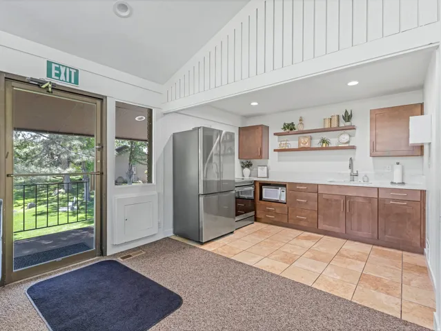 Kitchenette featuring stainless steel appliances, wood-finish cabinetry, white countertops, and tile flooring