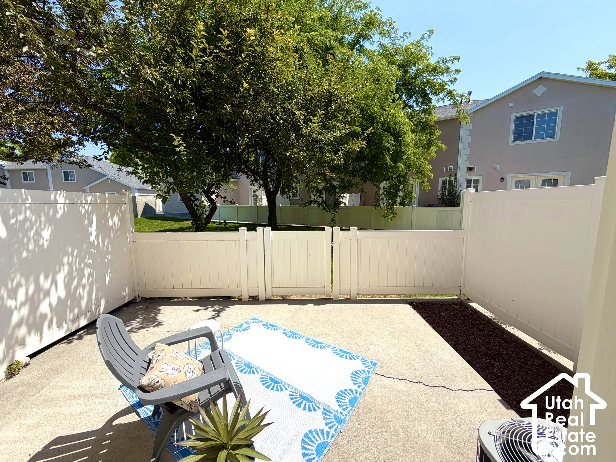 Private patio space featuring a concrete slab, white privacy fencing, and a mulched garden bed