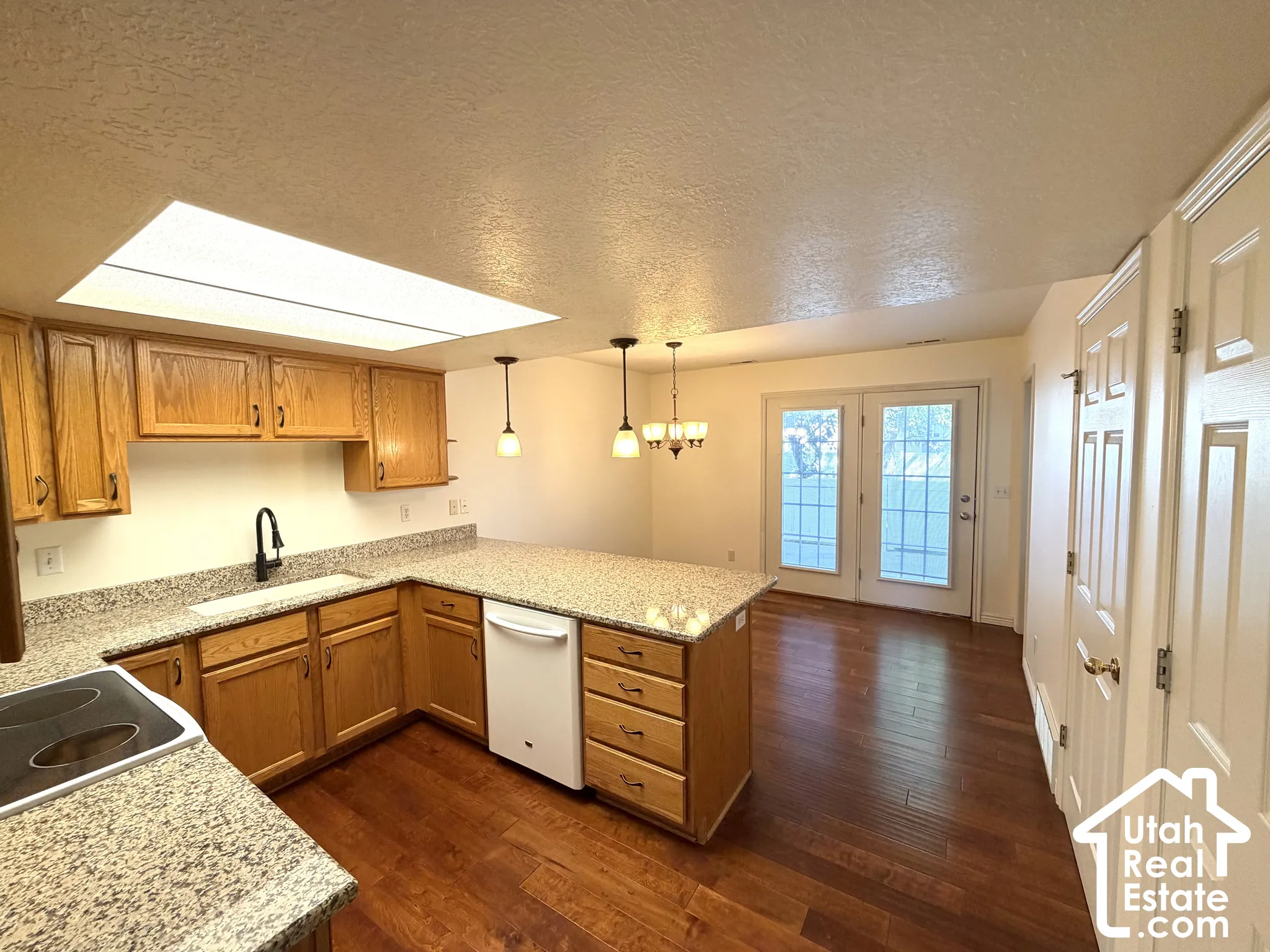 Kitchen featuring wood-finish cabinetry, granite countertops, an integrated dishwasher, and wood-finish flooring
