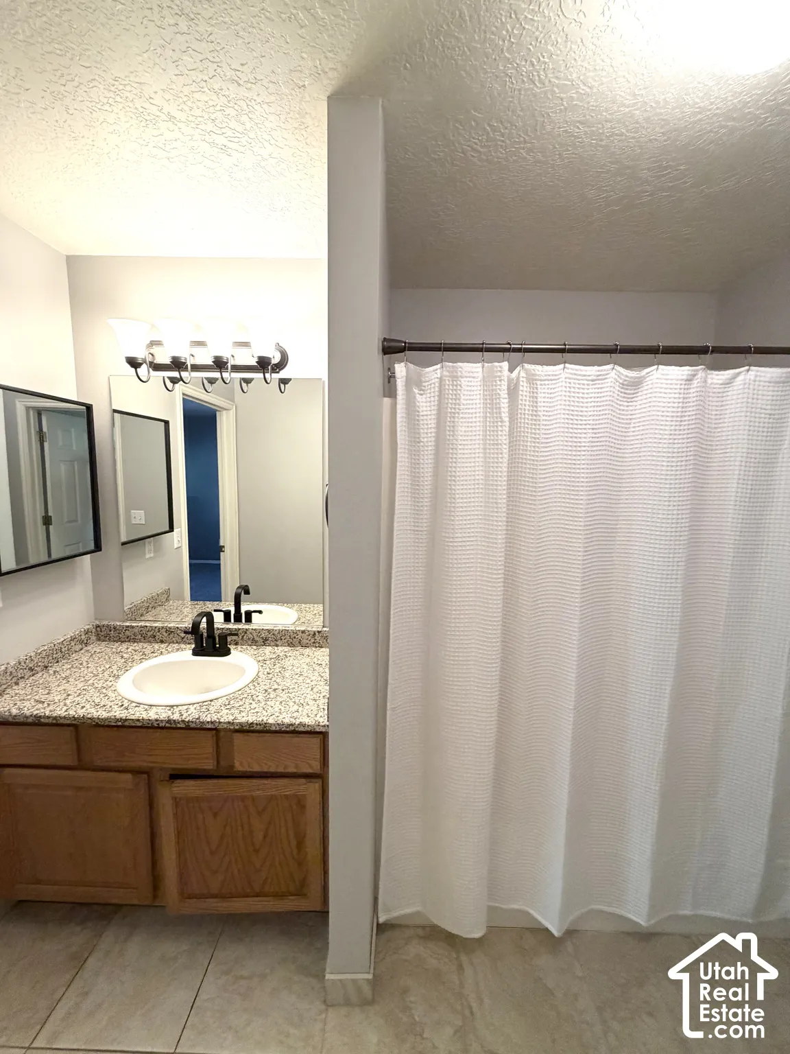 Bathroom featuring a vanity with a granite-look countertop, integrated sink, and wood-finish cabinetry