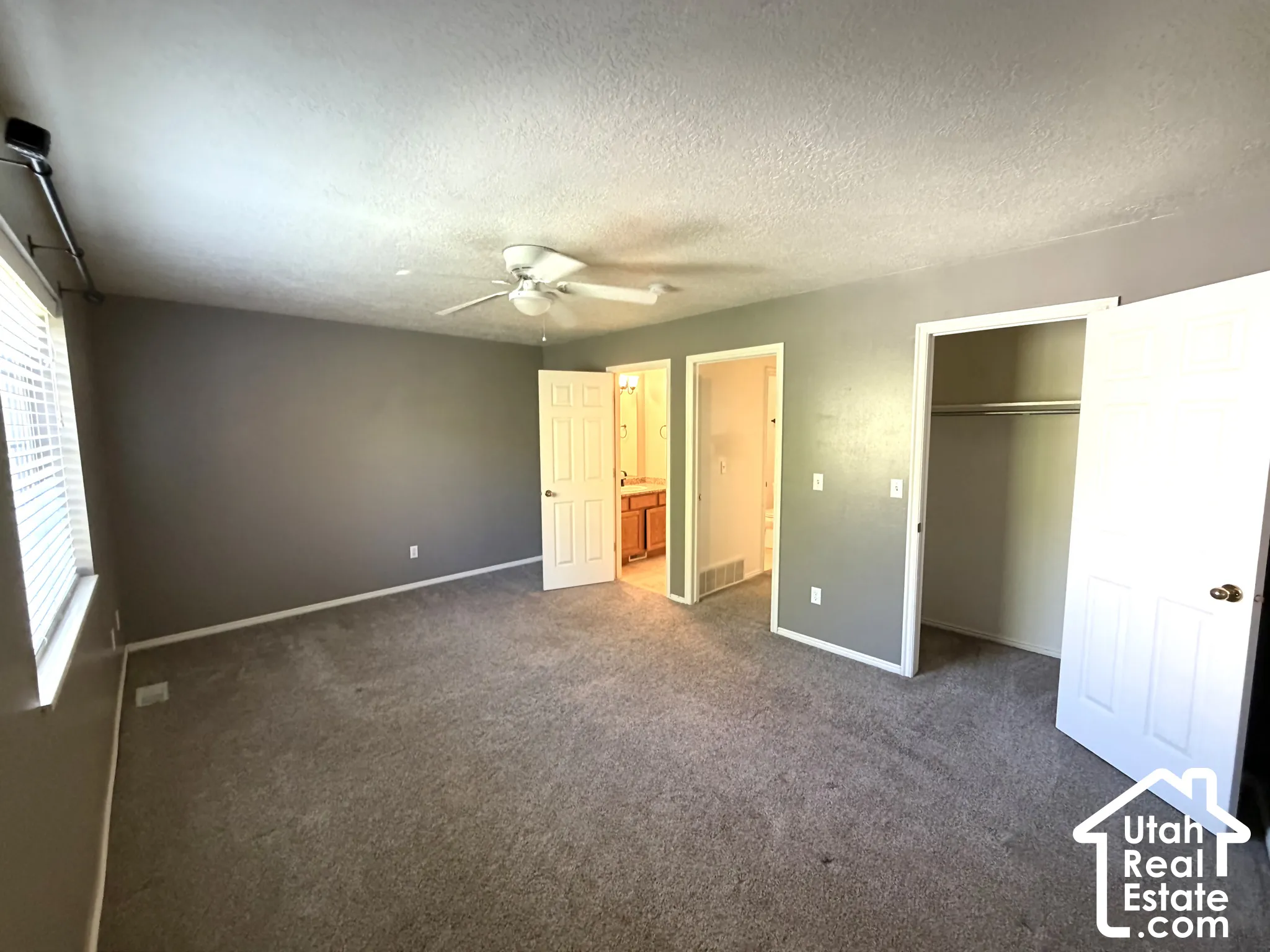 Carpeted room with a ceiling fan, window with blinds, and a built-in closet