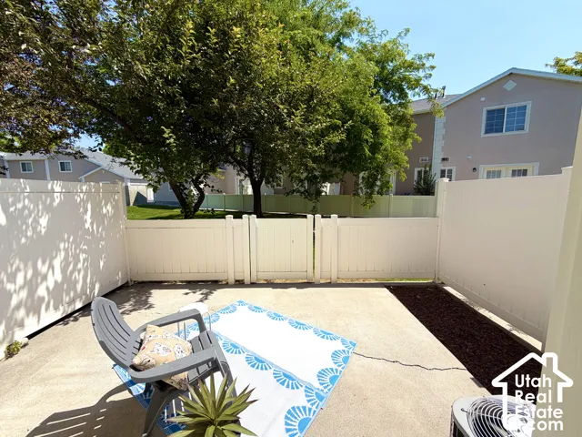 Private patio space featuring a concrete slab, white privacy fencing, and a mulched garden bed
