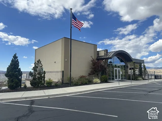 Contemporary building exterior with a curved glass entrance, stone accents, and an expansive paved parking area