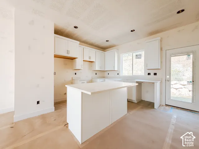 White shaker-style cabinetry, recessed lighting, and a kitchen island with a light-toned countertop