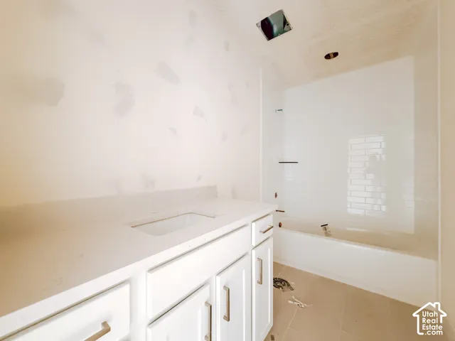 White vanity with dual doors and drawers, undermount sink, and a light-toned countertop