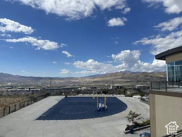 Outdoor amenity area featuring a covered pool, mountain backdrop, and surrounding cityscape
