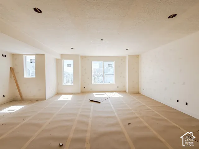 Spacious room with multiple windows providing natural light, recessed ceiling lighting, and neutral wall finishes