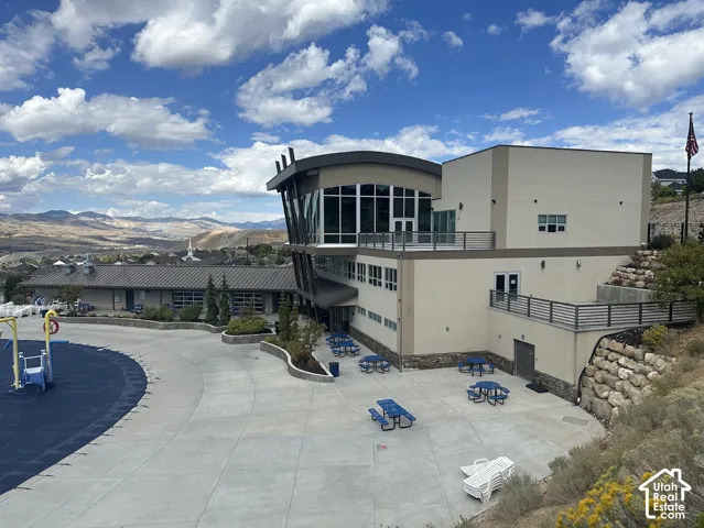 Modern architectural design with expansive windows, multi-level terraces, integrated landscaping, and a spacious paved patio