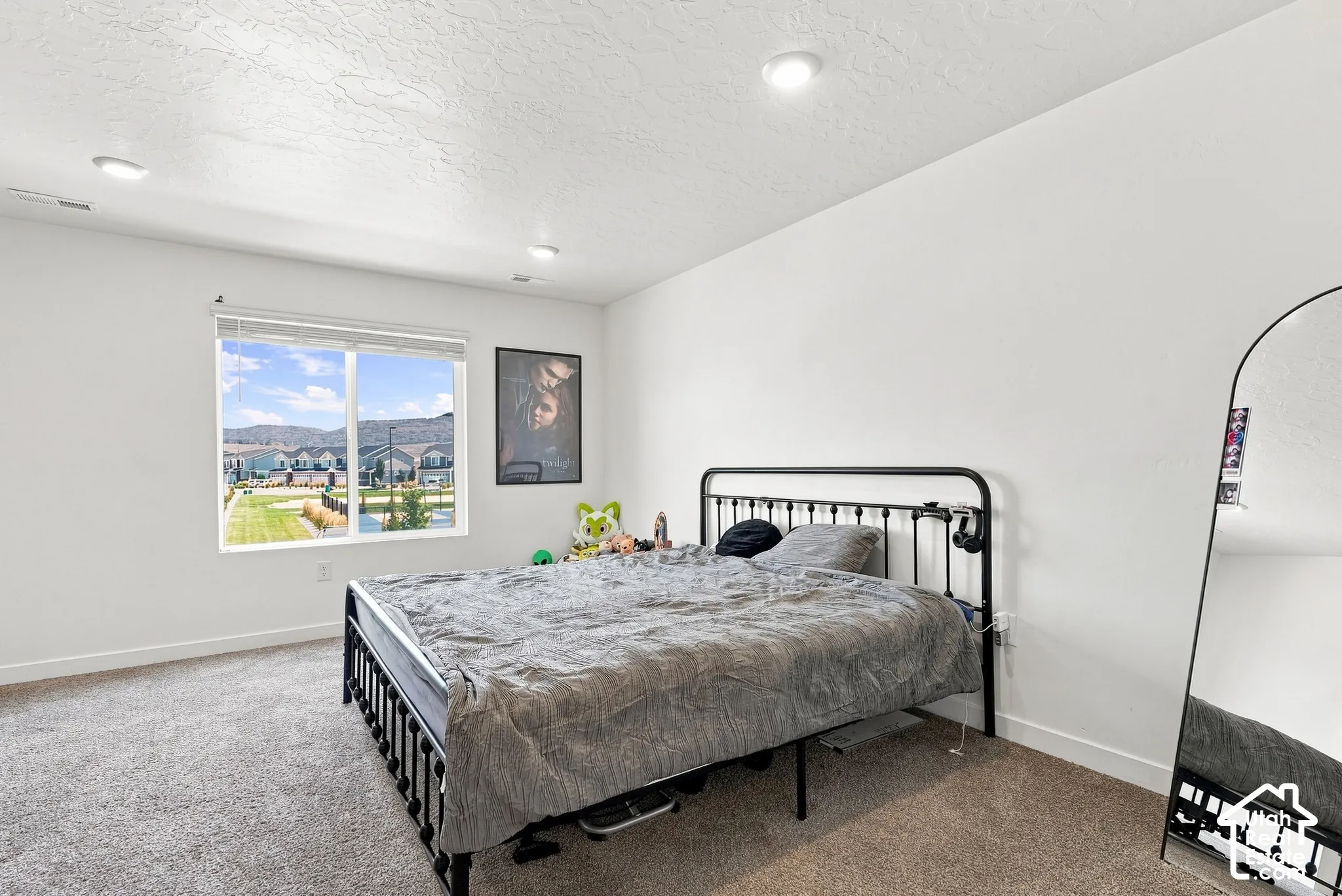 Recessed ceiling lighting, large window with blinds, light-toned wall paint, and textured ceiling finish
