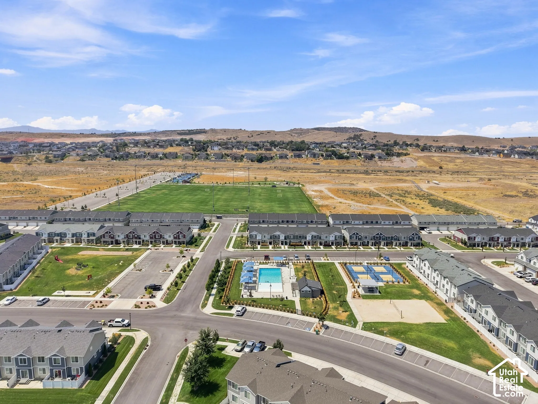 Community with townhomes, a large athletic field, swimming pool, volleyball court, and playground area