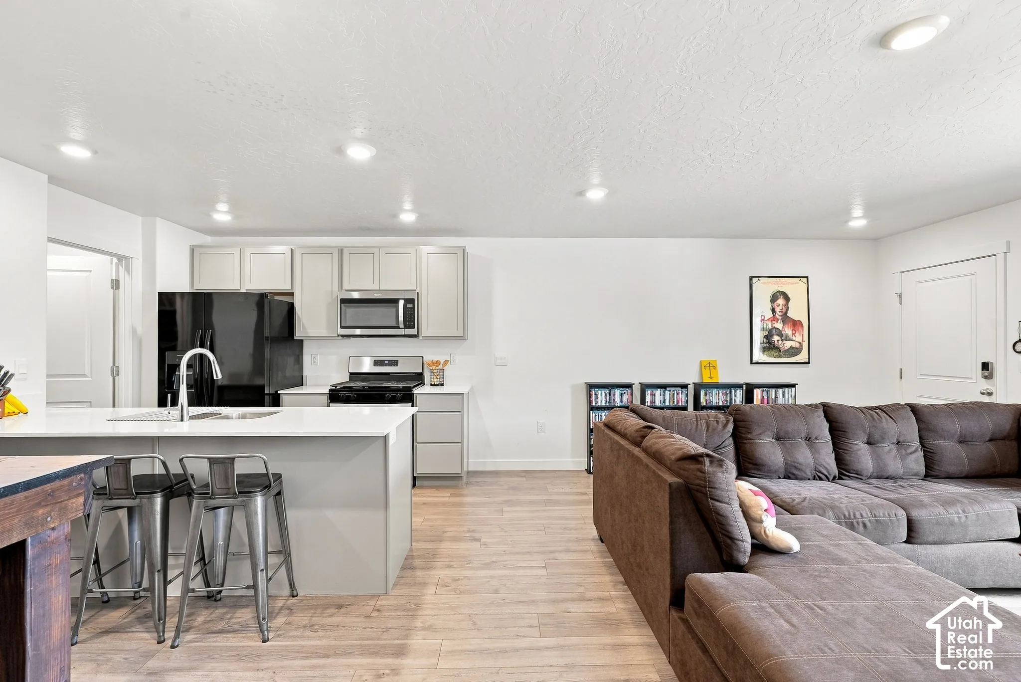 Open-concept living area with wood-finish flooring, recessed lighting, and a white color palette