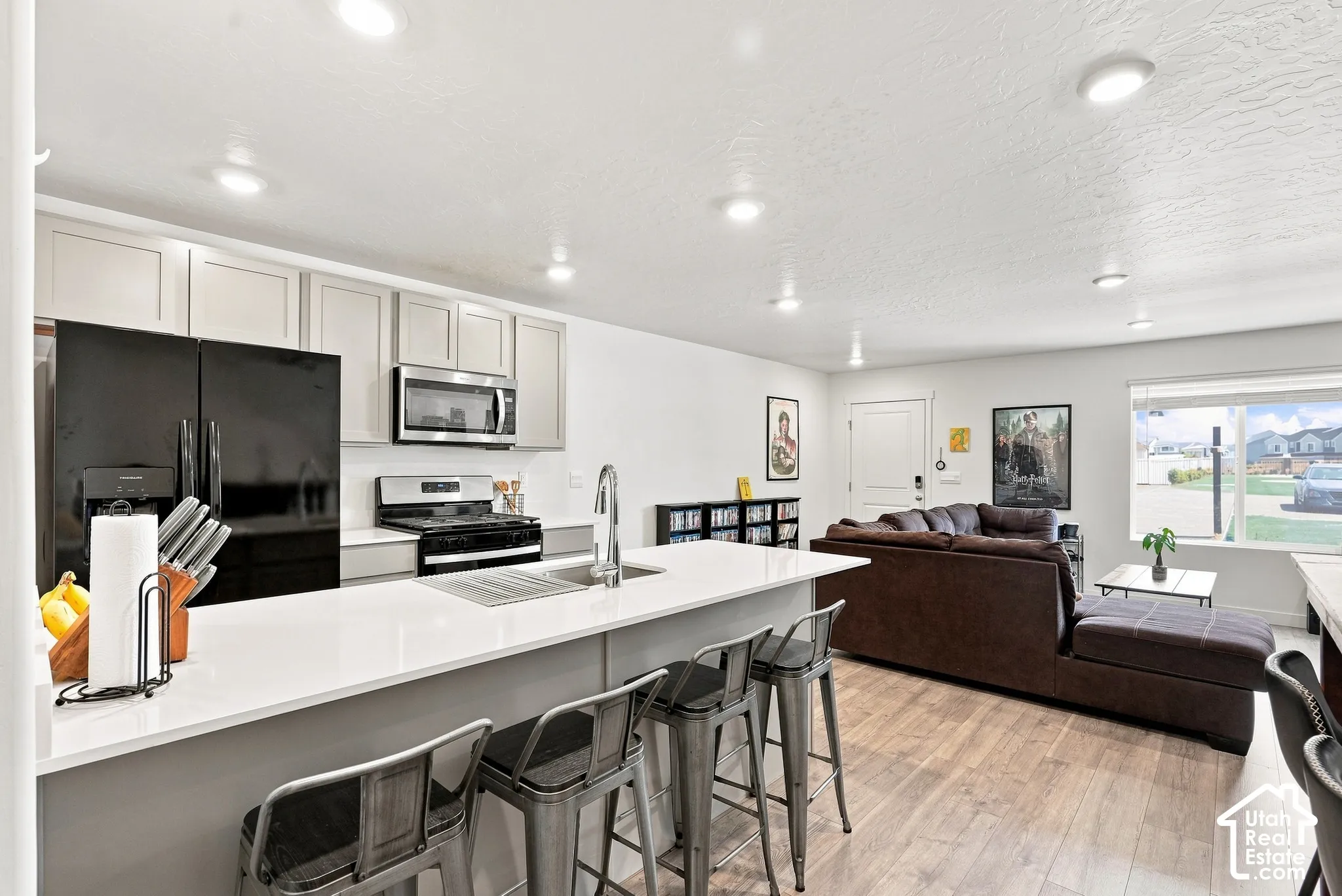 Kitchen island with white countertop, recessed lighting, wood-finish flooring, and light-toned cabinetry
