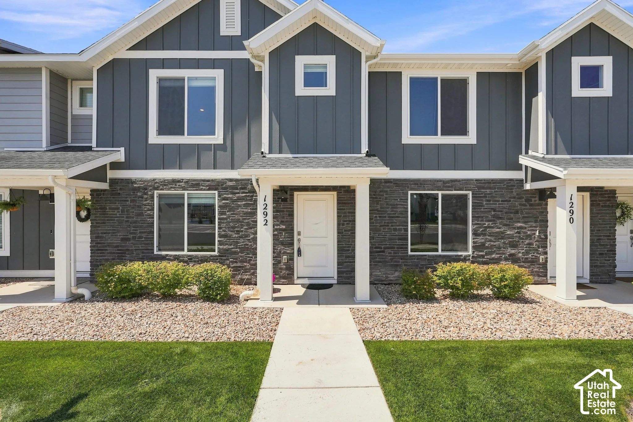 Exterior featuring board and batten siding, stone facade, covered entry, and a concrete walkway