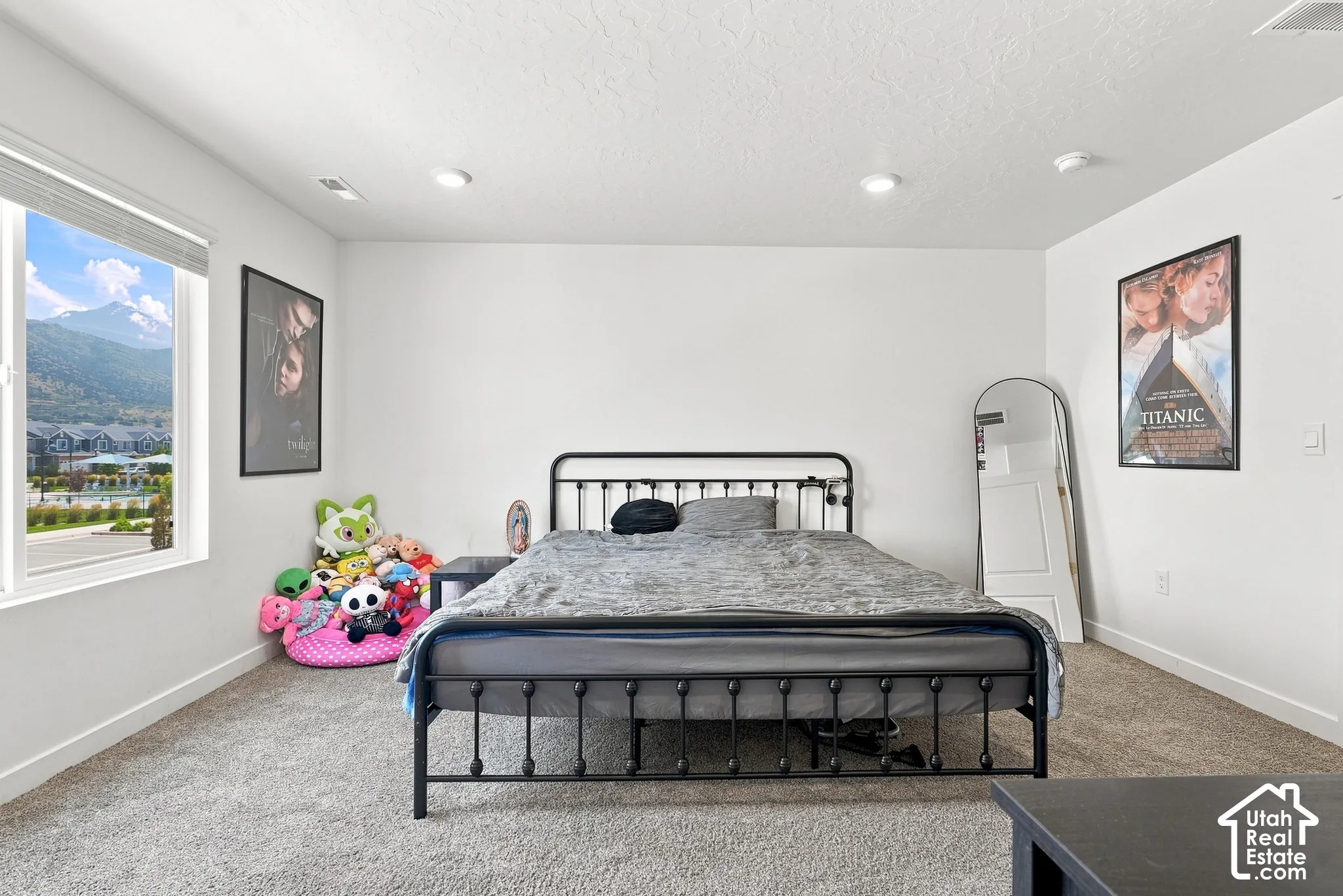 Recessed lighting, large window with mountain scenery, white walls, and gray carpet flooring