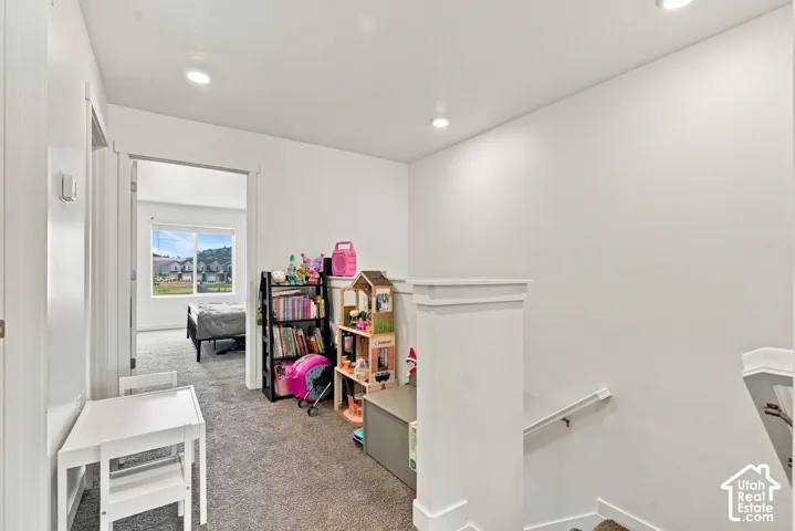Recessed lighting, light gray carpet, and white painted walls create a bright interior