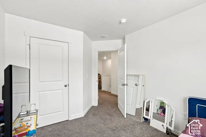 Plush carpet flooring, white painted walls, and white paneled doors with chrome hardware
