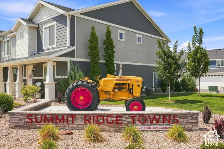 Stone-clad monument sign with raised lettering, gravel landscaping, and mature trees