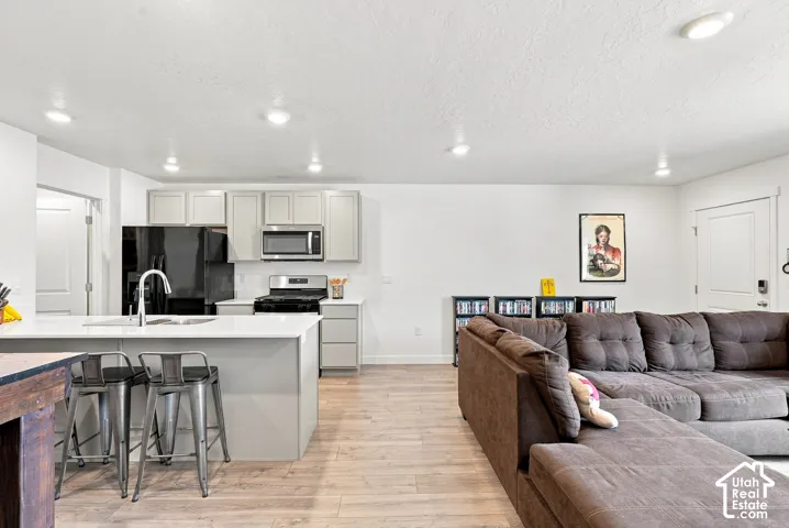 Open-concept living area with wood-finish flooring, recessed lighting, and a white color palette