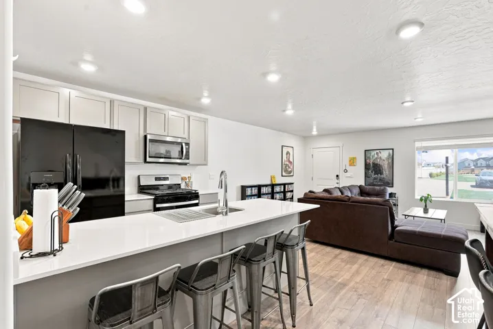 Kitchen island with white countertop, recessed lighting, wood-finish flooring, and light-toned cabinetry