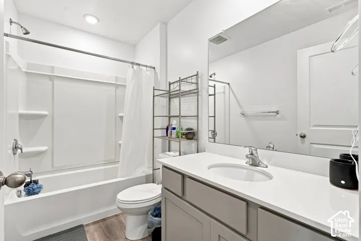 Integrated tub and shower combination, vanity with light gray cabinetry, white countertop, and large wall-mounted mirror
