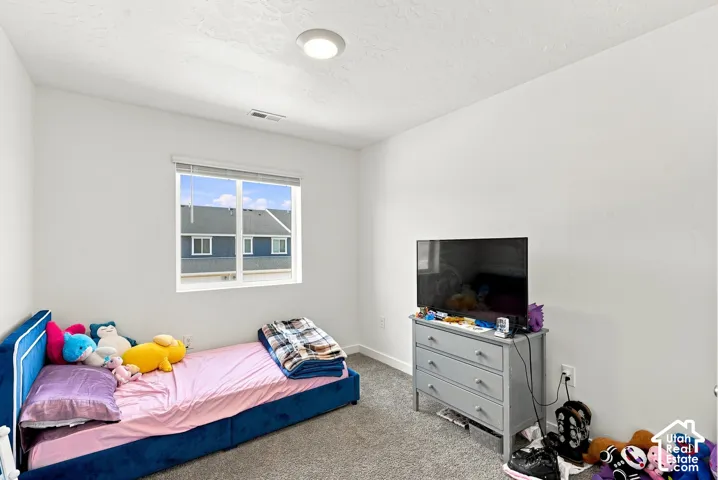Recessed ceiling light, white walls, carpeted flooring, and a single window with blinds