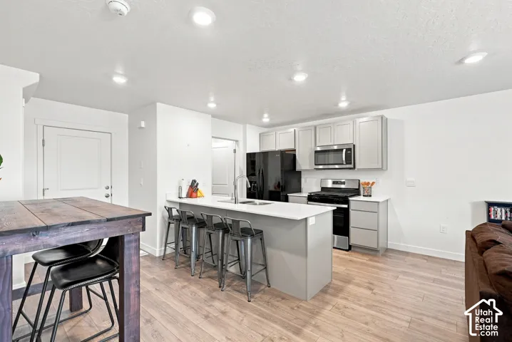 Open-concept kitchen with light wood-finish flooring, recessed lighting, and light gray cabinetry