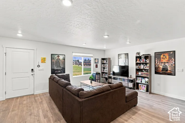 Wood-finish flooring, recessed lighting, and a white interior door