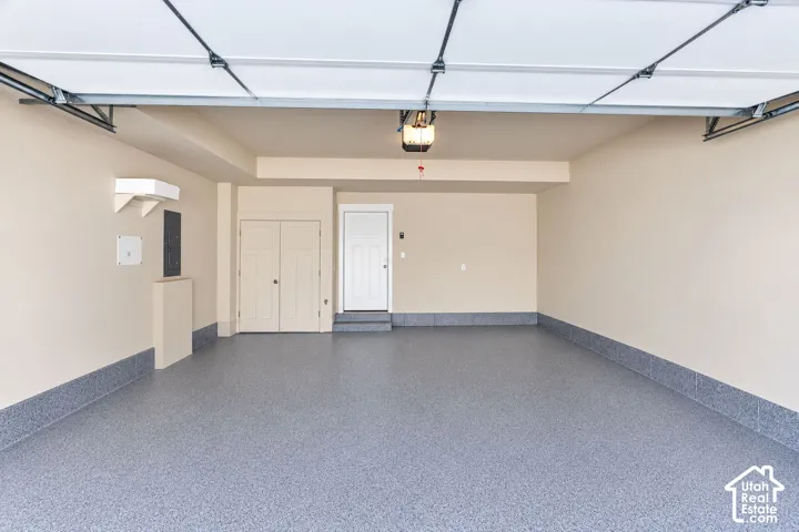 Attached garage featuring a coated concrete floor, neutral wall paint, overhead garage door system, and built-in storage closet