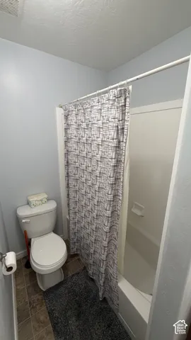Tub and shower combination with a white surround and white porcelain toilet