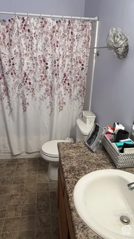 Vanity with integrated sink, wood-finish cabinetry, and a textured countertop