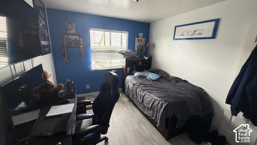 Recessed windows with horizontal blinds, wood-finish flooring, and painted accent wall