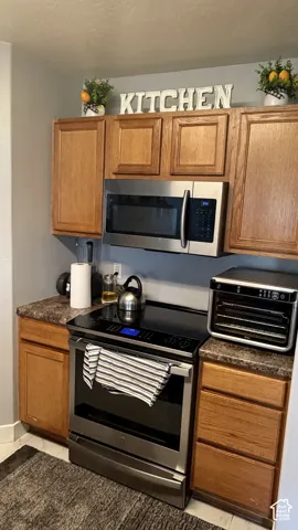 Wood-finish cabinetry paired with a built-in stainless steel microwave and matching range