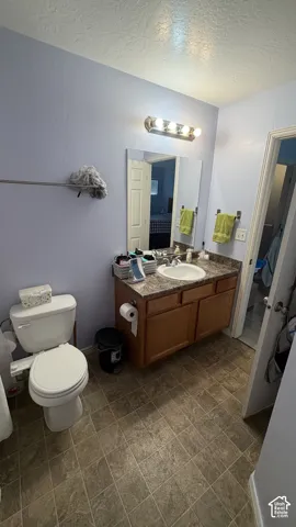 Vanity with wood-finish cabinetry, integrated sink, and patterned countertop