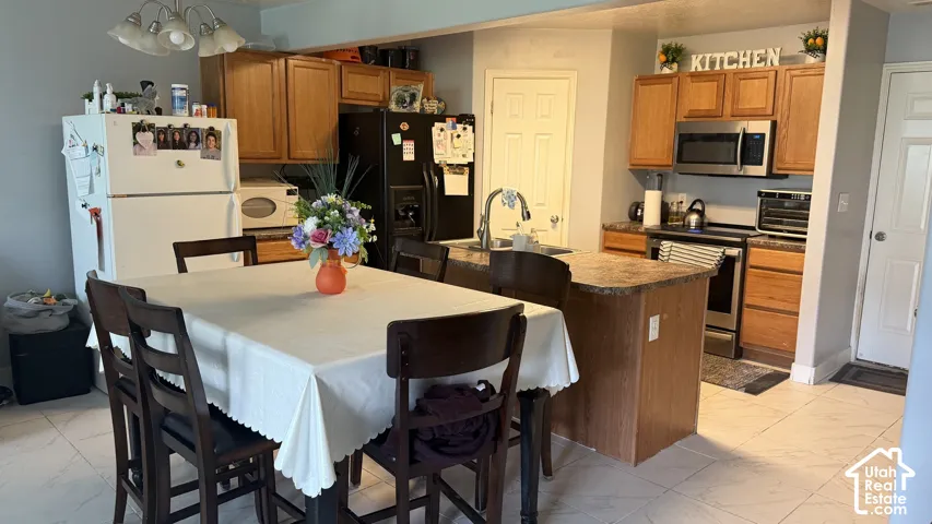 Kitchen featuring wood cabinetry, an island with a built-in sink, and stainless steel appliances