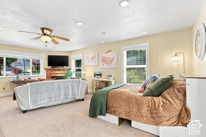 Recessed lighting, wood-finish ceiling fan, wood-frame fireplace, and multiple windows with blinds