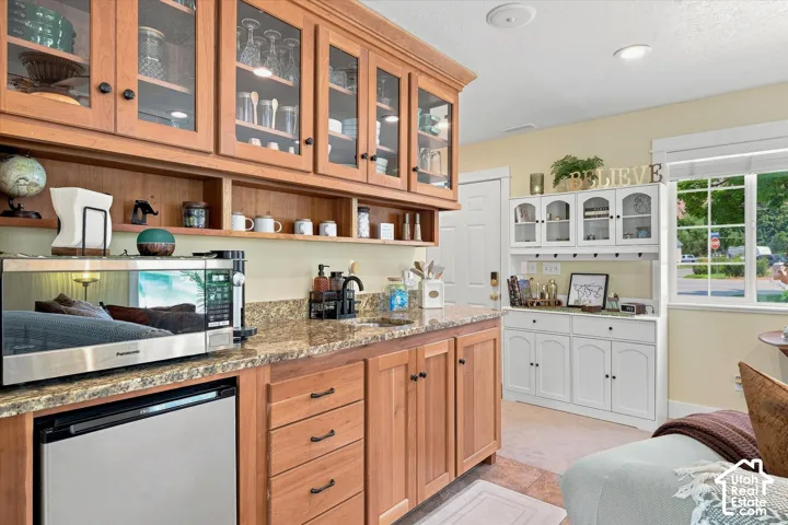 Built-in cabinetry with glass-front uppers and under-cabinet shelving, granite-style countertop, stainless steel appliances, and a dedicated sink