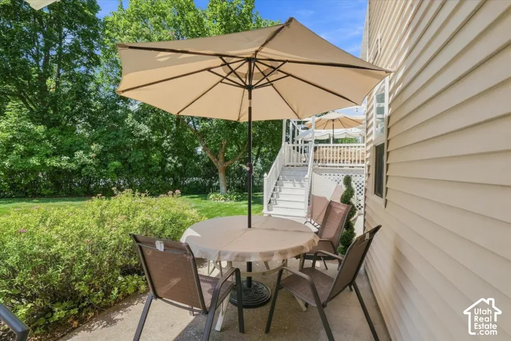 Concrete patio with a privacy umbrella, surrounded by lush green landscaping and mature trees