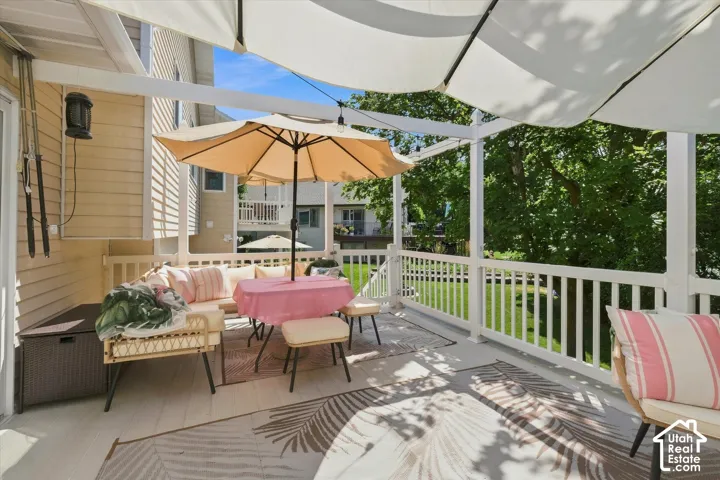 Covered outdoor deck with white railing and privacy screens, featuring a light-toned exterior wall