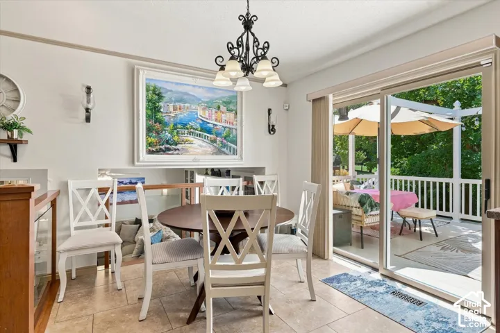 Tiled flooring, overhead chandelier, sliding glass door, deck with white railing