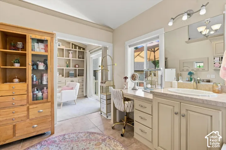 Built-in vanity with integrated sink, expansive mirror with track lighting, and a window for natural light
